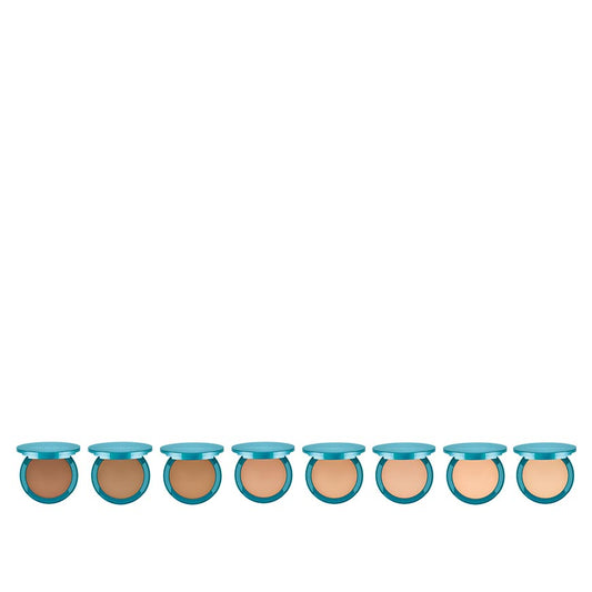 A collection of twelve pressed foundation bottles, with a light beige to dark brown color range, each with a blue cap.